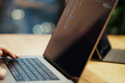 A person typing on a laptop on a wooden table