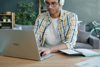 Man wearing headphones working on a laptop at a desk