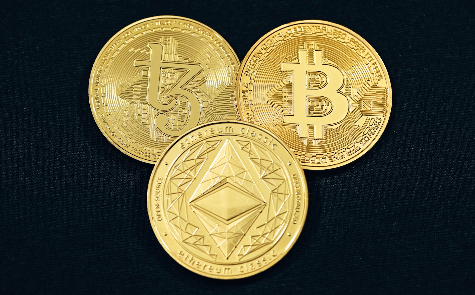 three gold bitcoins on a black background