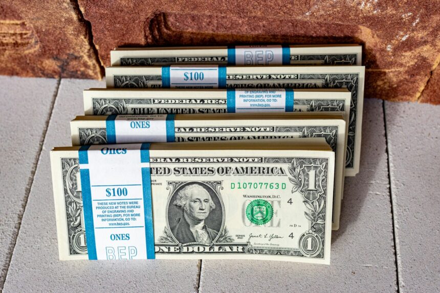 three stacks of one hundred dollar bills on a tile floor