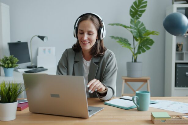 Woman wearing headphones works on a laptop at desk.